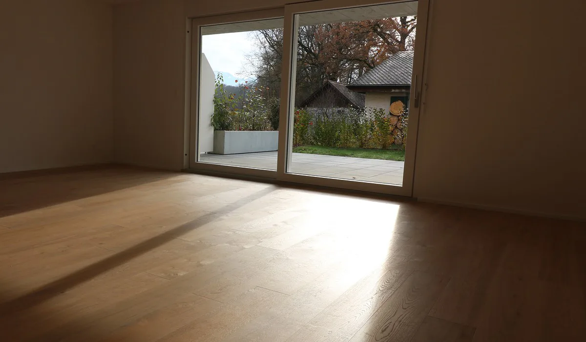 Le séjour d'un logement livré par Cimmeco, parquet chêne et lumière rasante par la baie